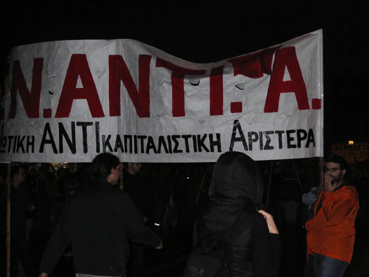 a group of people walking near a white protest sign