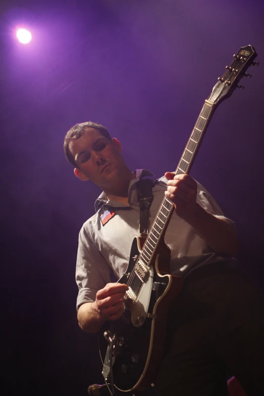 a young man playing guitar and singing into the microphone