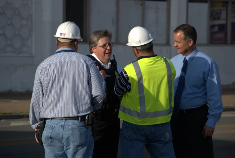 three men standing outside talking to each other