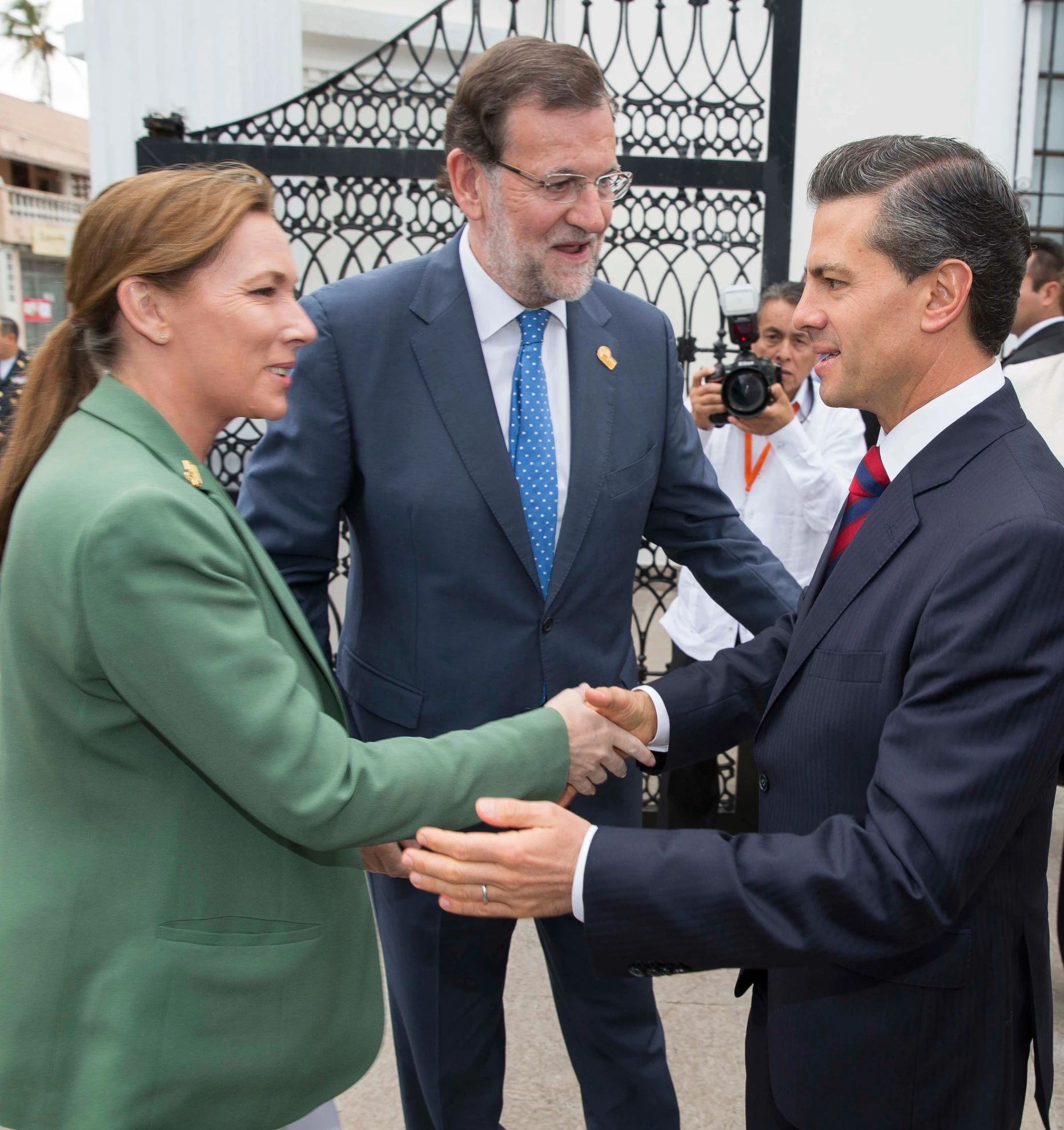 two men and a woman shaking hands outside a building