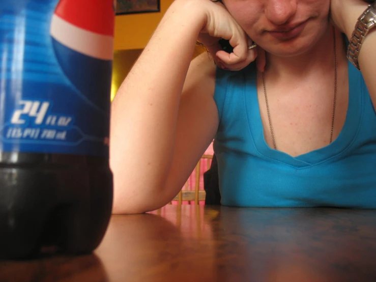 there is a woman sitting in front of a coke bottle