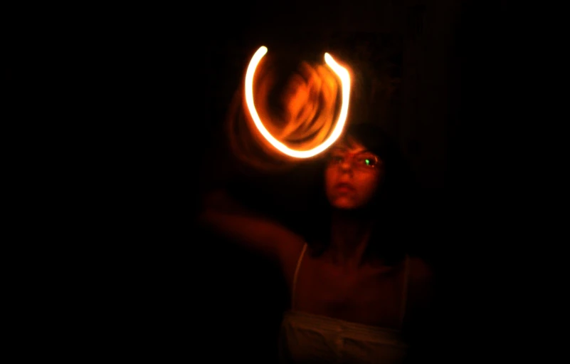 a woman holding a fire hula hoop in the dark
