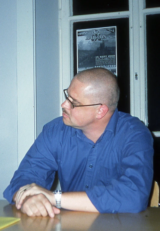 a man in a blue shirt sitting at a table