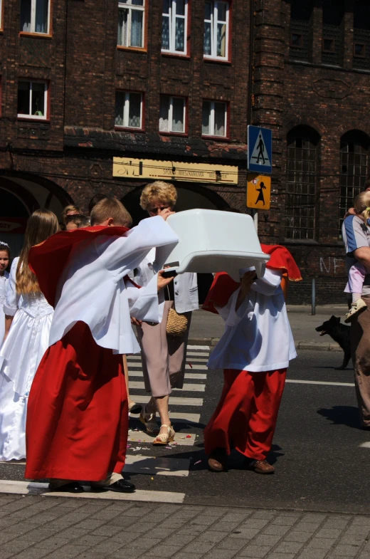 two people in costumes carry a white sheet across a city street