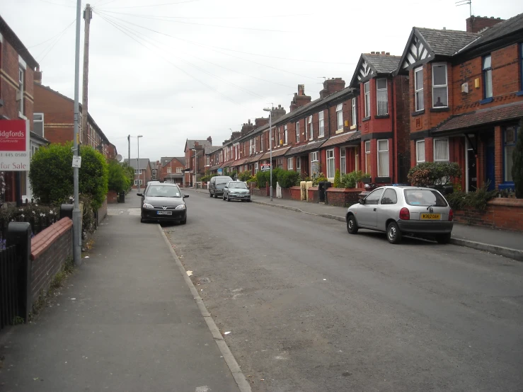 a street with cars parked along it and several brick row houses in the back