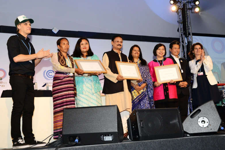 people hold their awards on stage during an event