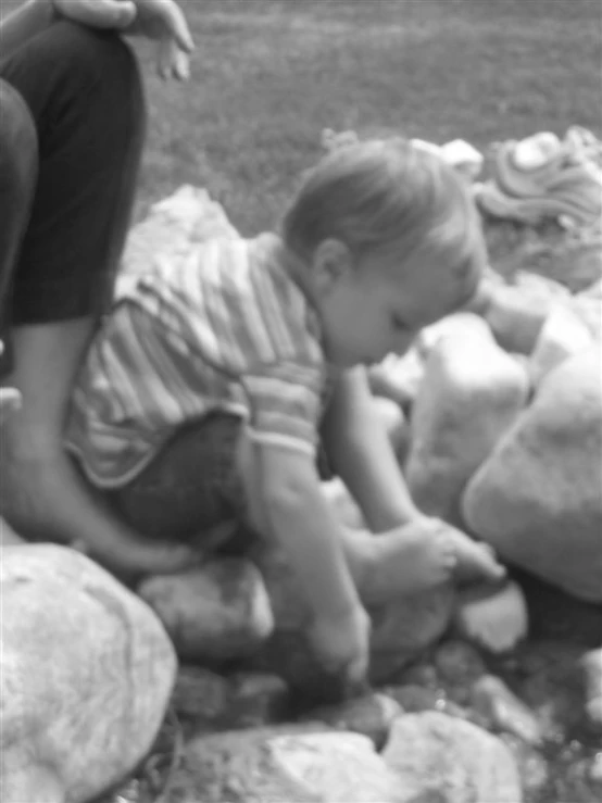 a black and white po of a toddler playing with rocks