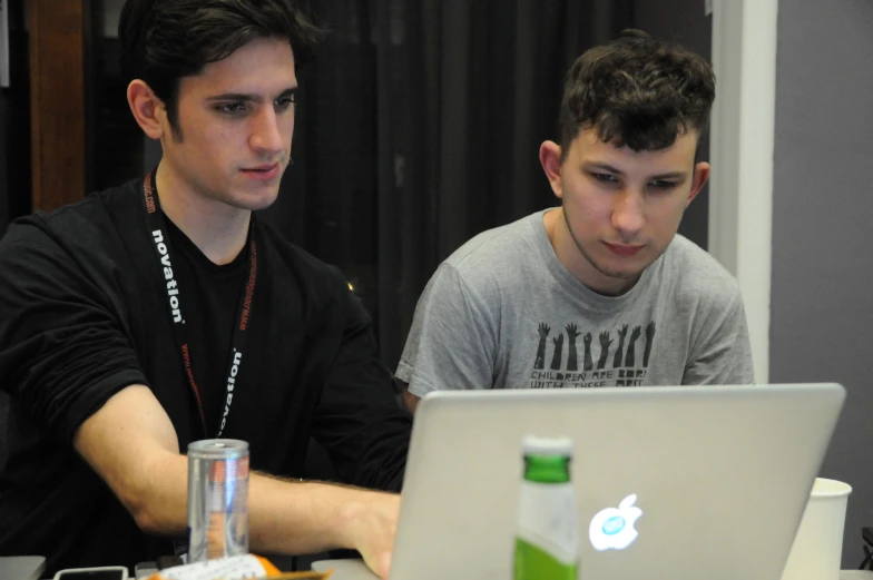 two men sitting side by side working on their laptops