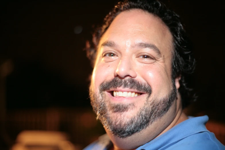 man in blue shirt and beard smiling at camera