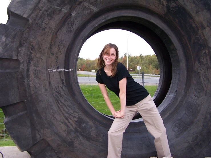 a lady posing for a po next to giant tires