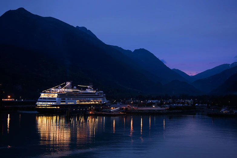 the cruise ship is anchored in the bay at twilight