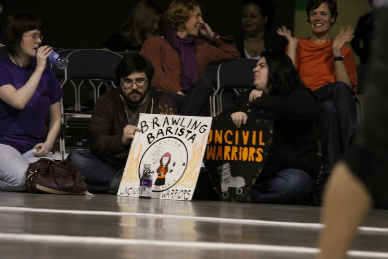 a young man sitting in front of a sign surrounded by a crowd