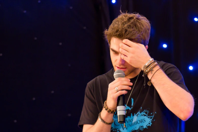 a male singer holding a microphone while he talks