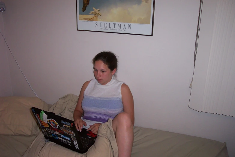 a girl sitting on the bed looking at a laptop