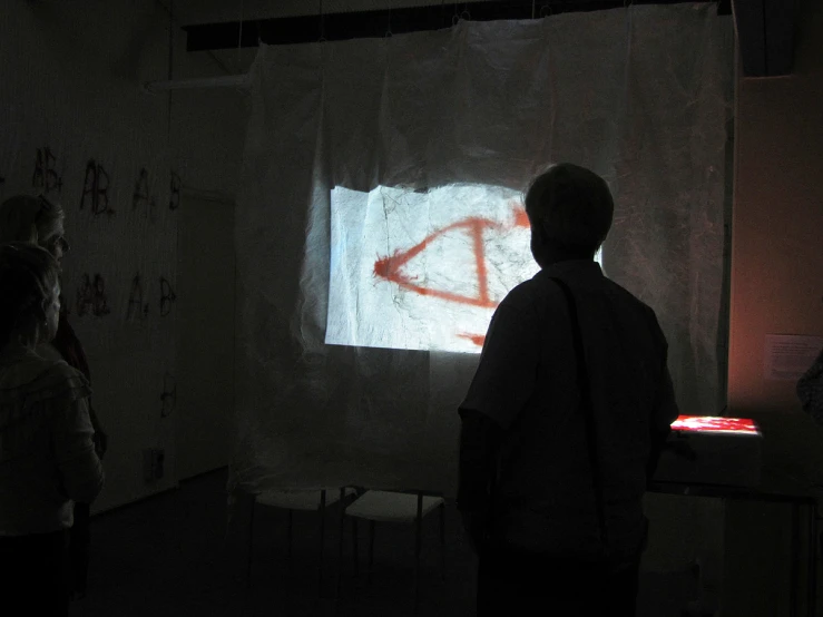 three people looking at an artwork on a wall