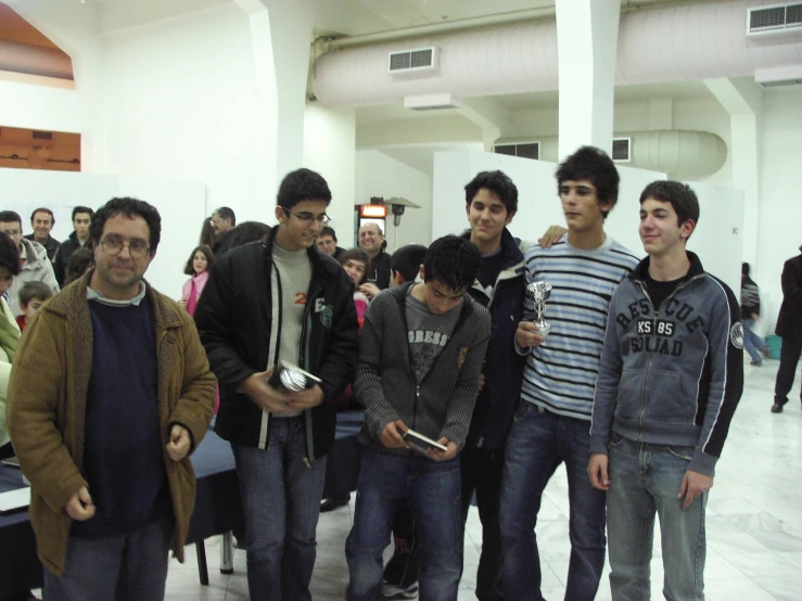 four guys standing next to each other with people in the background