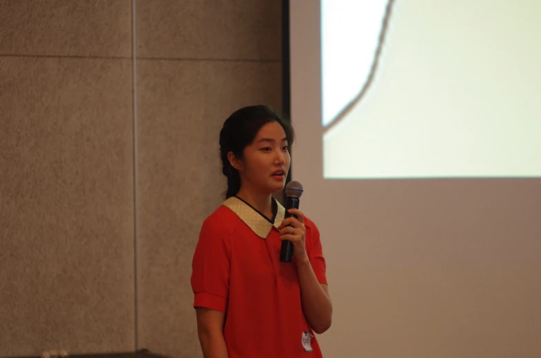 young lady speaking with microphone in large room