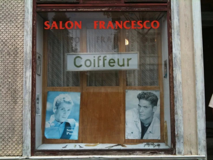 a hair salon with posters on the window of it