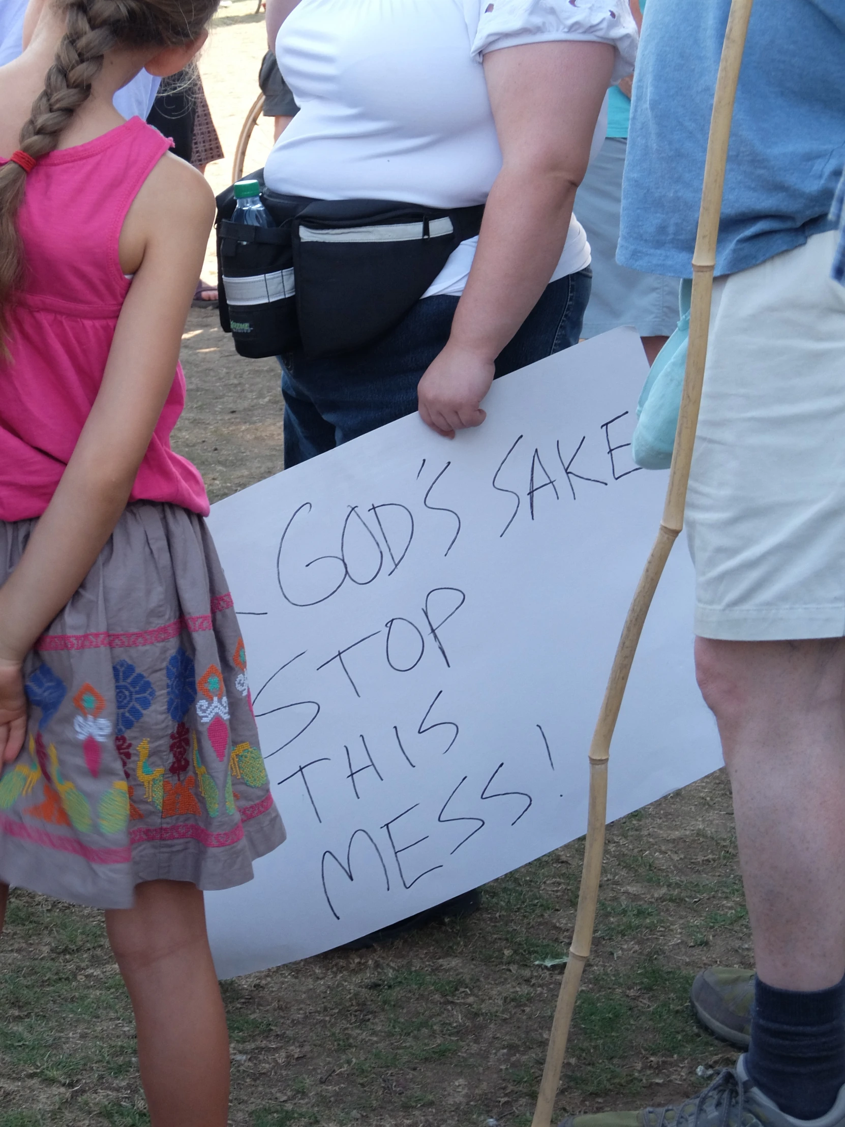 a small girl in a dress standing in front of a sign