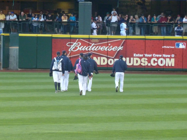 a group of people in baseball uniforms standing on a field