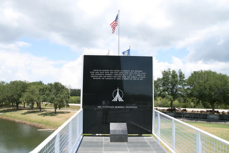 a memorial marker on a sidewalk by a body of water