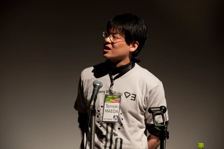 a young asian boy is standing by a microphone