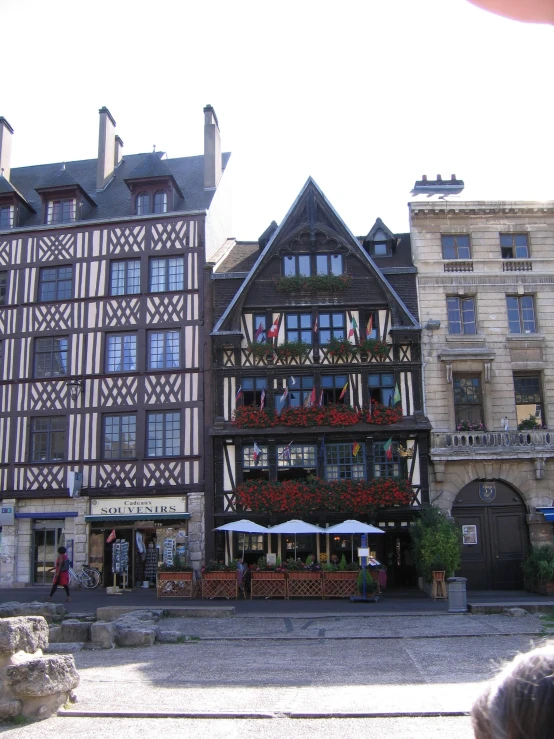 a building with flowers on the balcony and lots of people