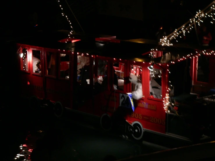 people on a red trolley train lit up at night