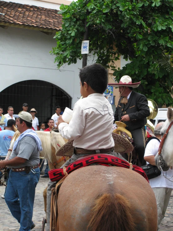 several people in traditional dress ride horses through a town square