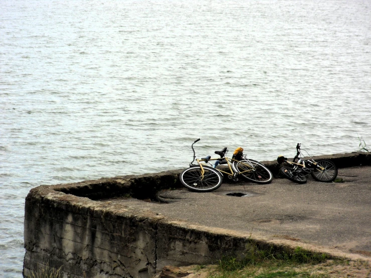 two bicycles are parked against a concrete ledge overlooking the water