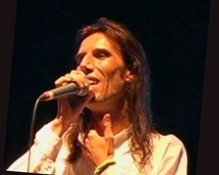 man singing on a stage and holding his face up to his mouth