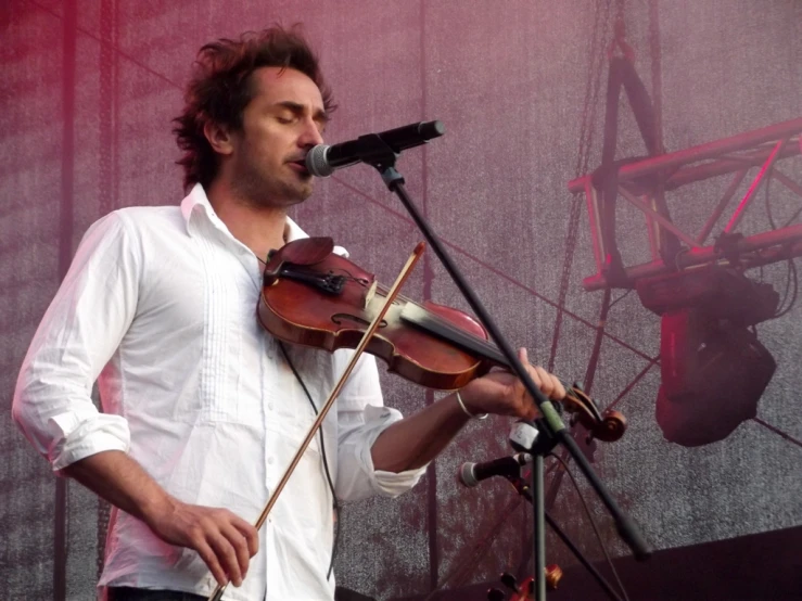 man playing the violin with a microphone on stage