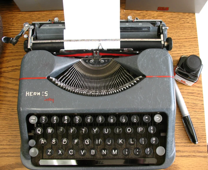a grey typewriter is set on a desk next to a note