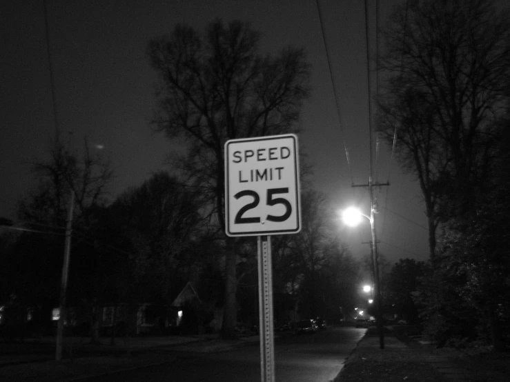 a speed limit sign lit up by street lights