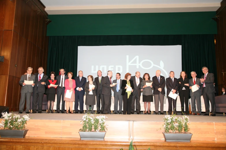 several people stand on a stage in front of a stage curtain