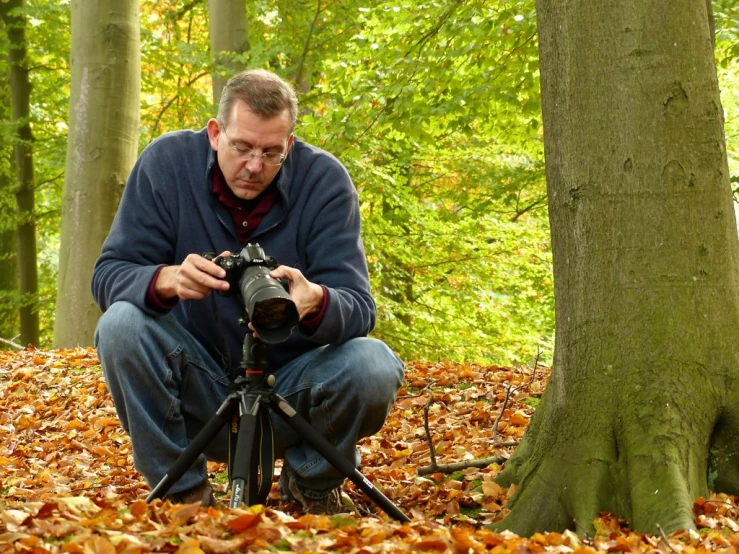 a man crouches on the ground to take pictures