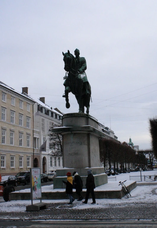 two people are standing near a statue of a man on a horse