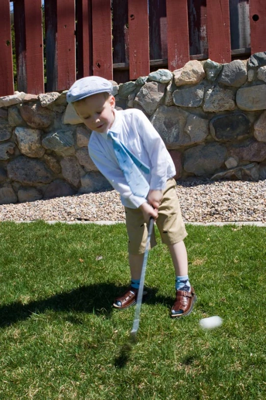 a little boy playing croquet on the grass