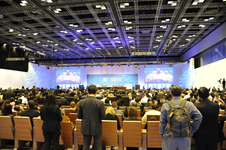 people are gathered in a large conference hall for a lecture