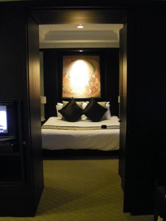 an open doorway leads to a bed and television in a bedroom