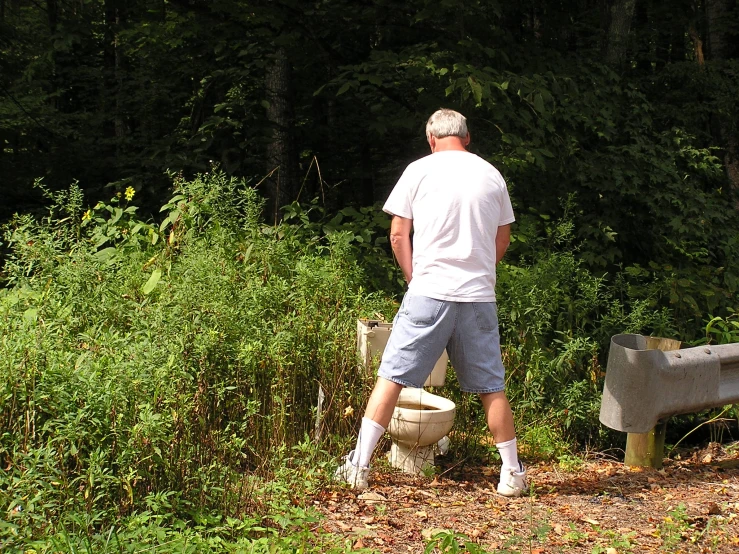 a man is standing next to a bench with a toilet in it