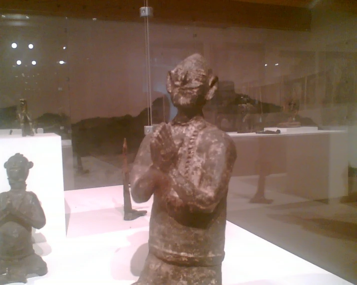 there are sculptures on display behind glass in a museum