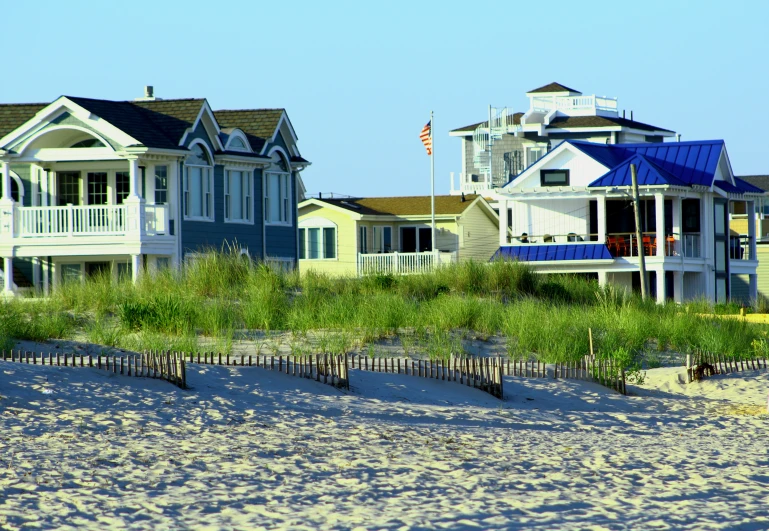 houses are standing on the beach by tall grass