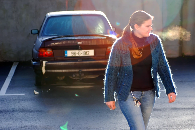 a woman crossing the street with her car nearby