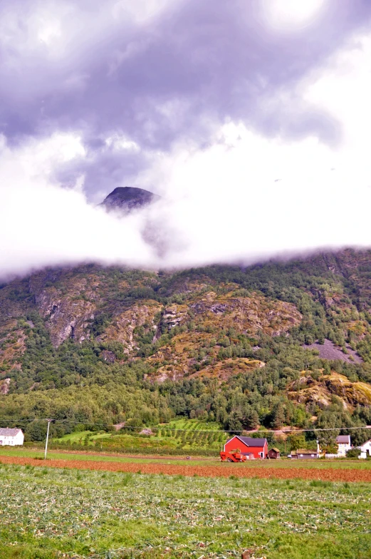 there are many clouds and buildings near the mountain