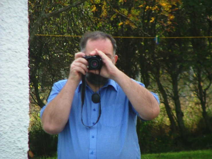 a man taking a po of himself in front of some trees