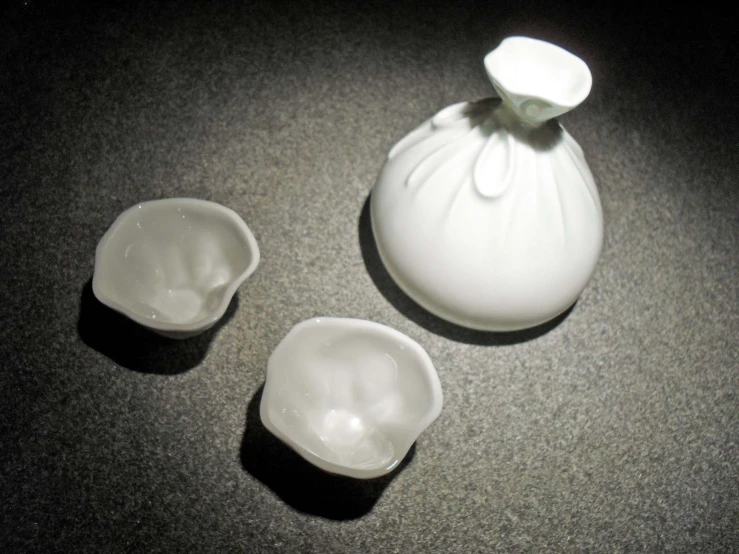 a white vase sitting on a counter next to two empty bowls