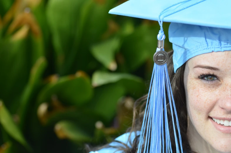 a girl in a cap and gown smiles with her graduation tassel on