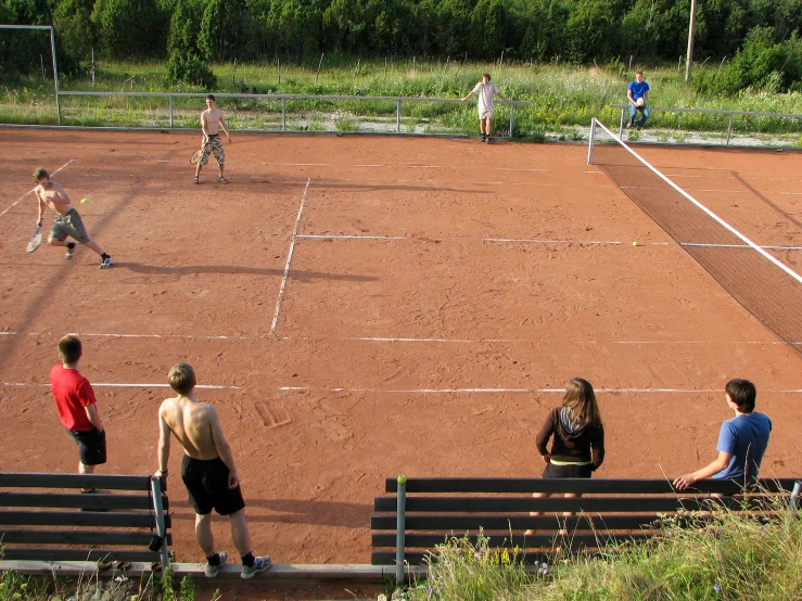 a tennis court with several players watching the match
