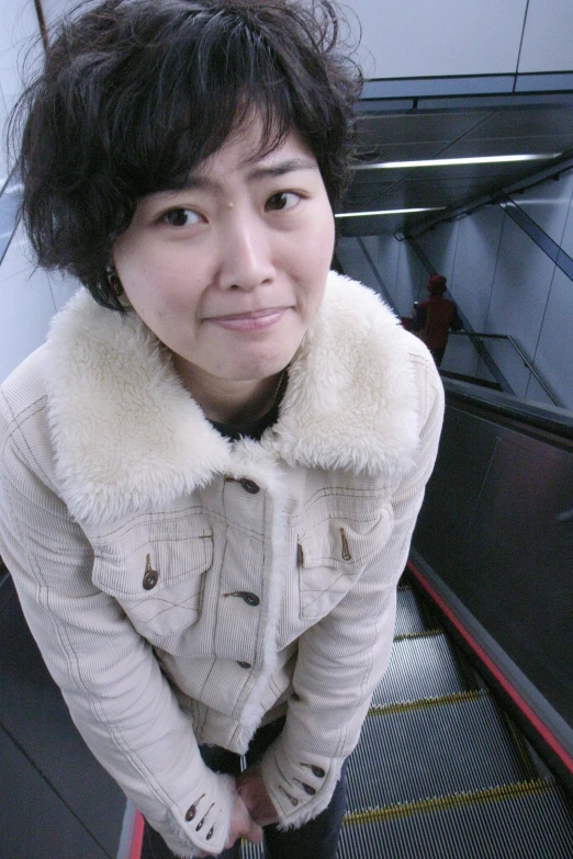 a woman standing on an escalator smiling for the camera